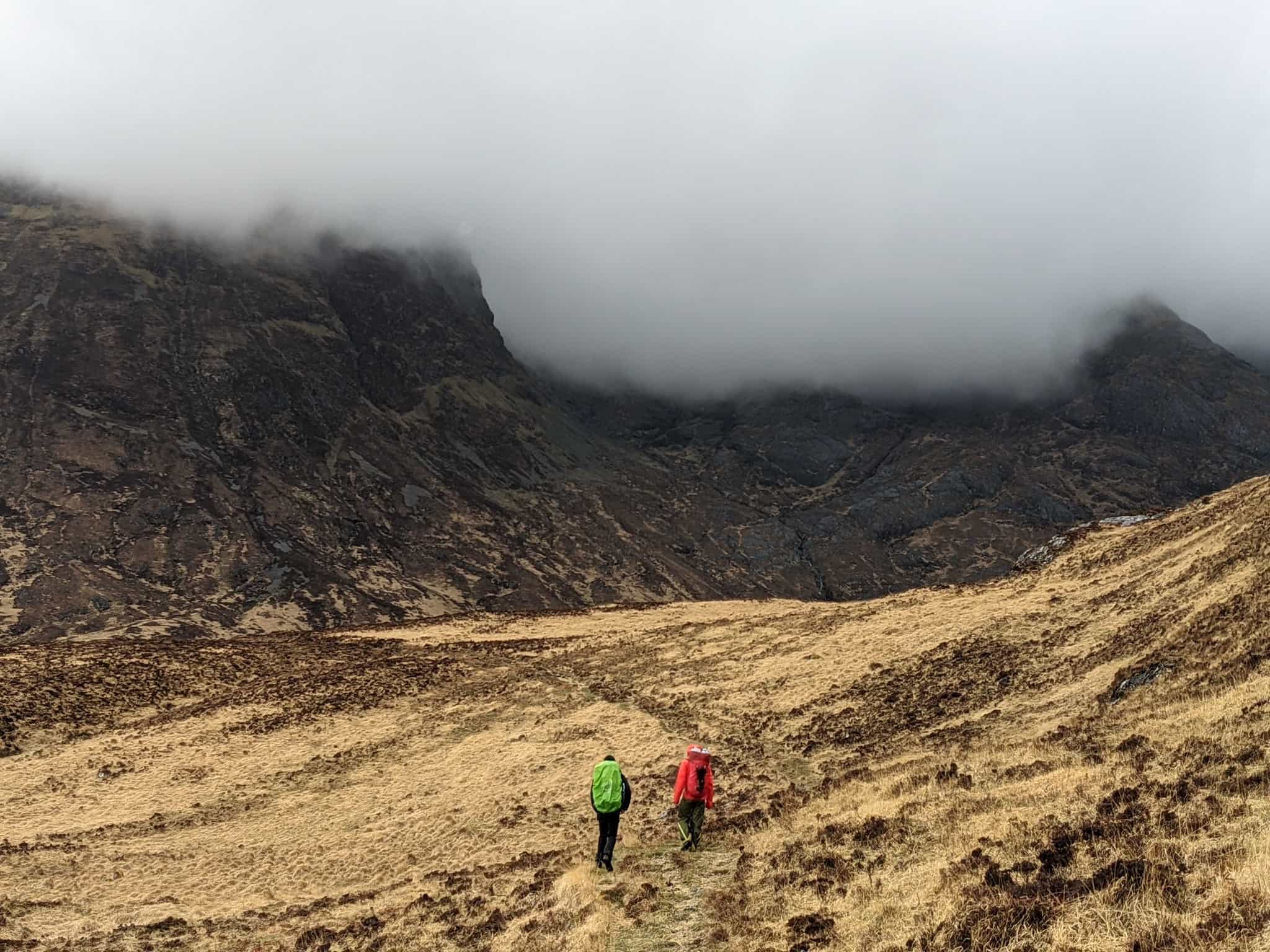 Moody clouds settling on the mountains above two hiker on Scotland's Isle of Rum.