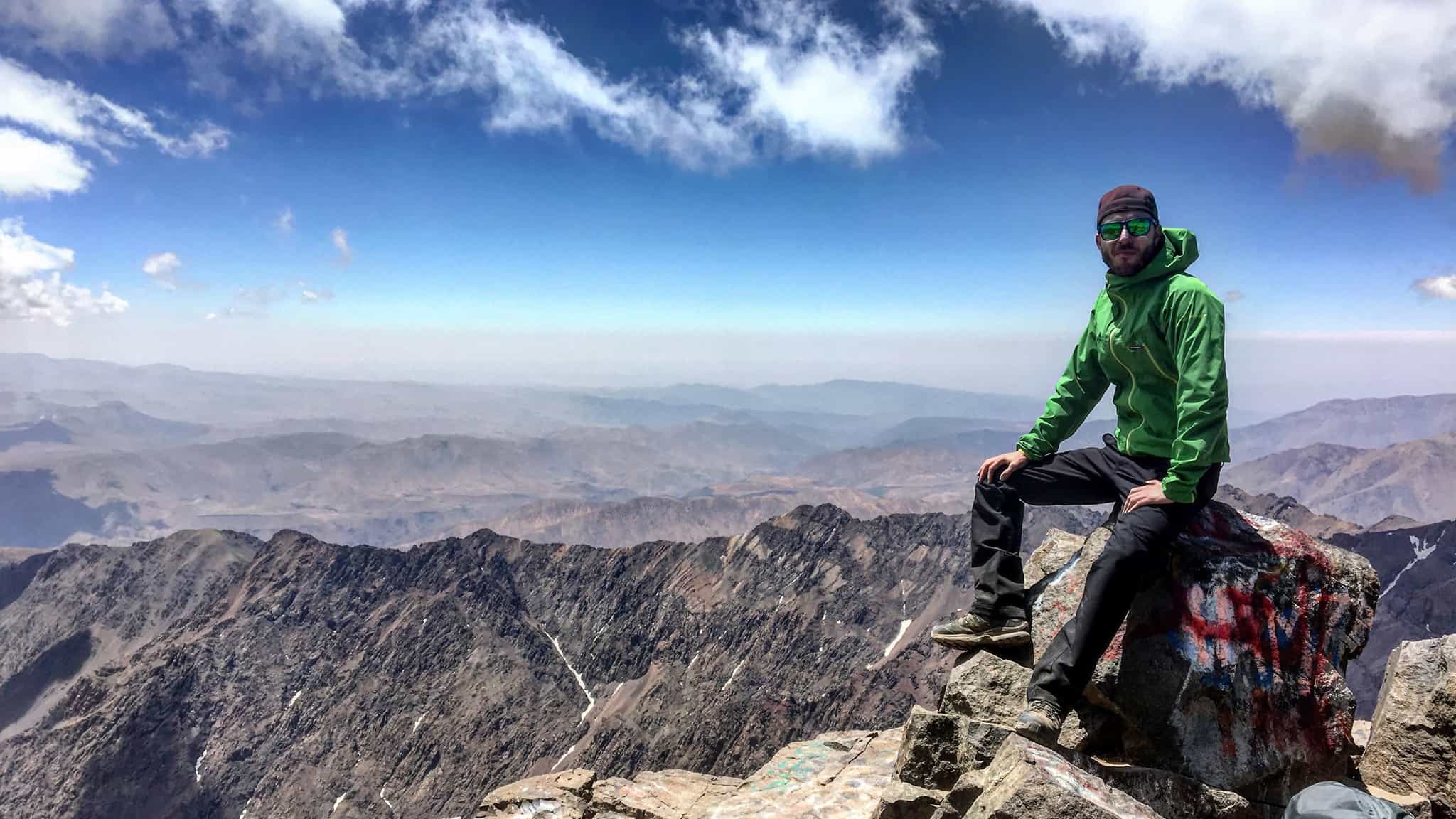 A male hiker relaxes on a rock at the summit Morocco's Mount Toubkal.