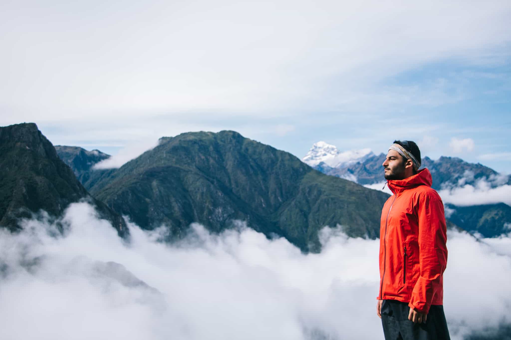 Man overlooks the mountains above the clouds on the Salkantay Trek in Peru.
