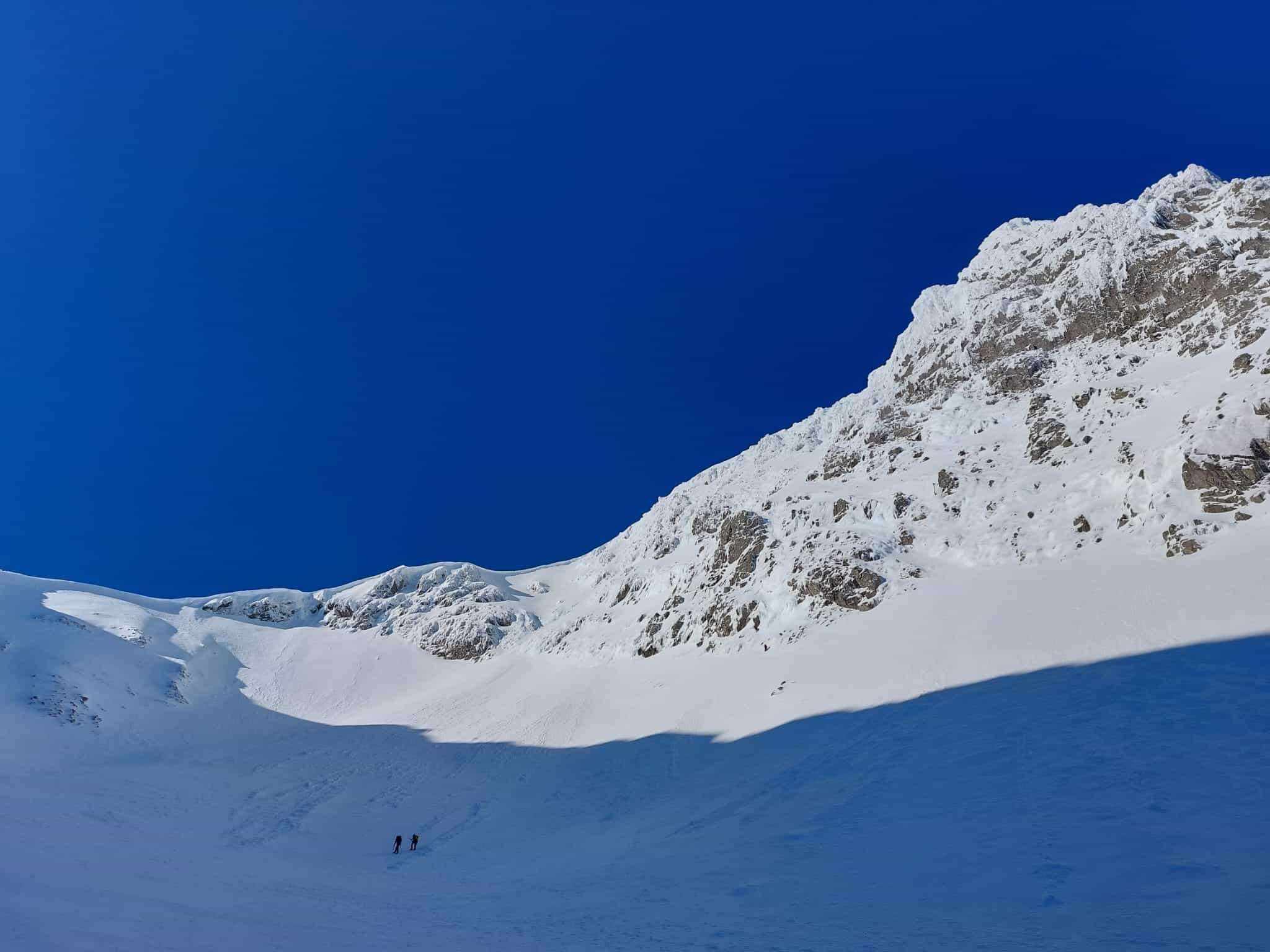 Two hikers from a distance on Ben Nevis, Scotland, covered with snow.