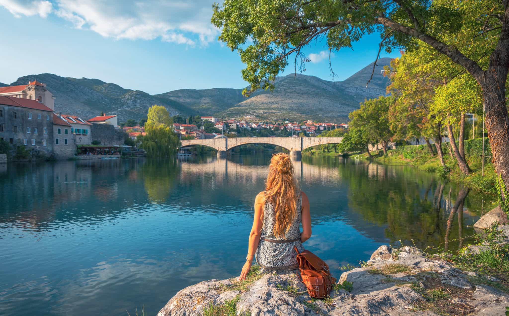 Women sitting next to the river by Trebinje Bridge