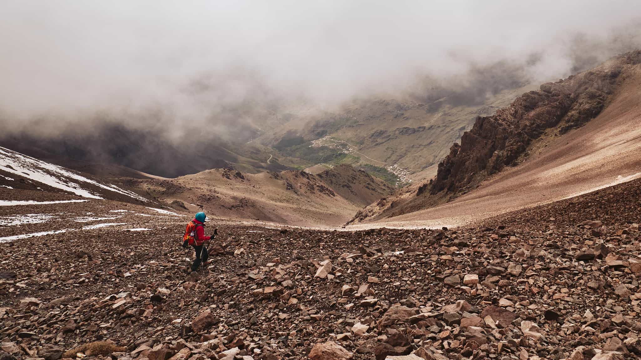 Hiker descends down a scree mountain pass in Morocco's Atlas Mountains