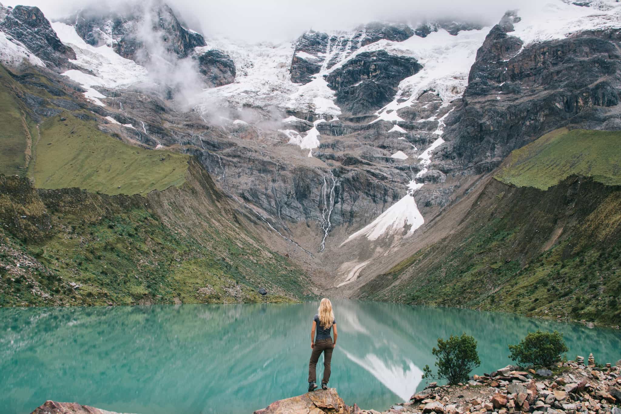 Female hiker overlooking Humantay Lake under the snowy Andes mountains behind