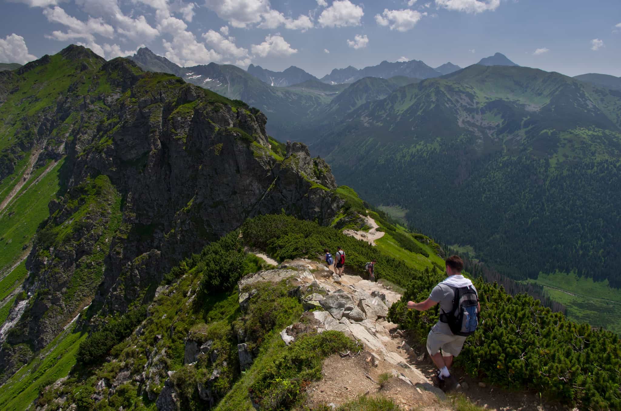Hikers walking along a green ridge in the Tatra Mountains