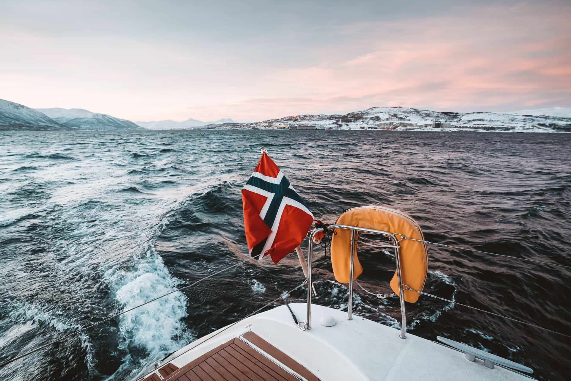 POV from the back of a boat in the Arctic circle, with the Norwegian flag. Photo: Host
