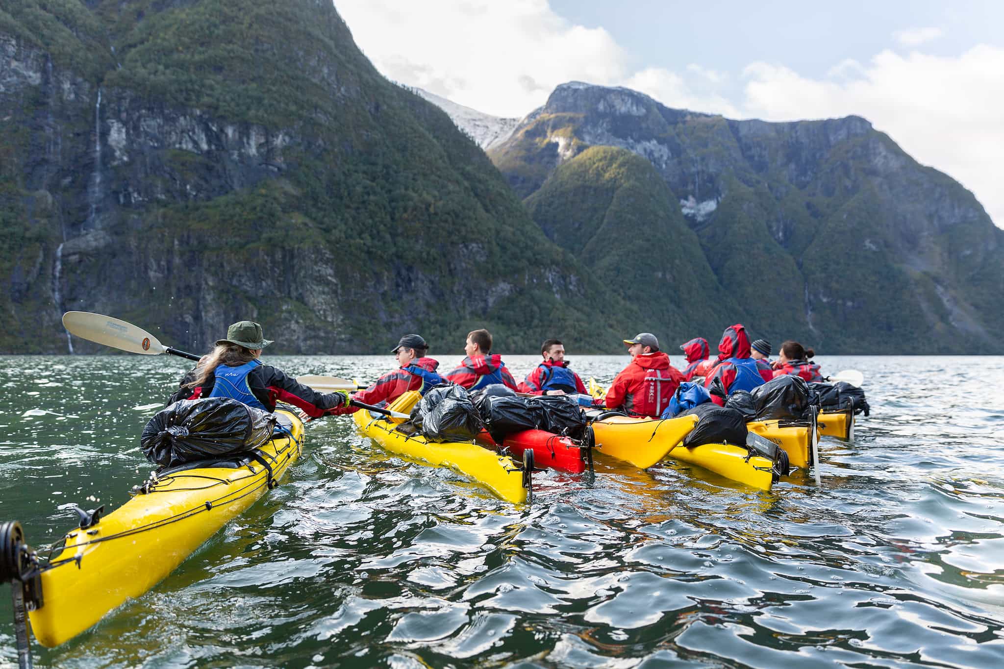 A group of kayakers stop for a rest on the waters of the Naeroyfjord in the Norwegian Fjords.