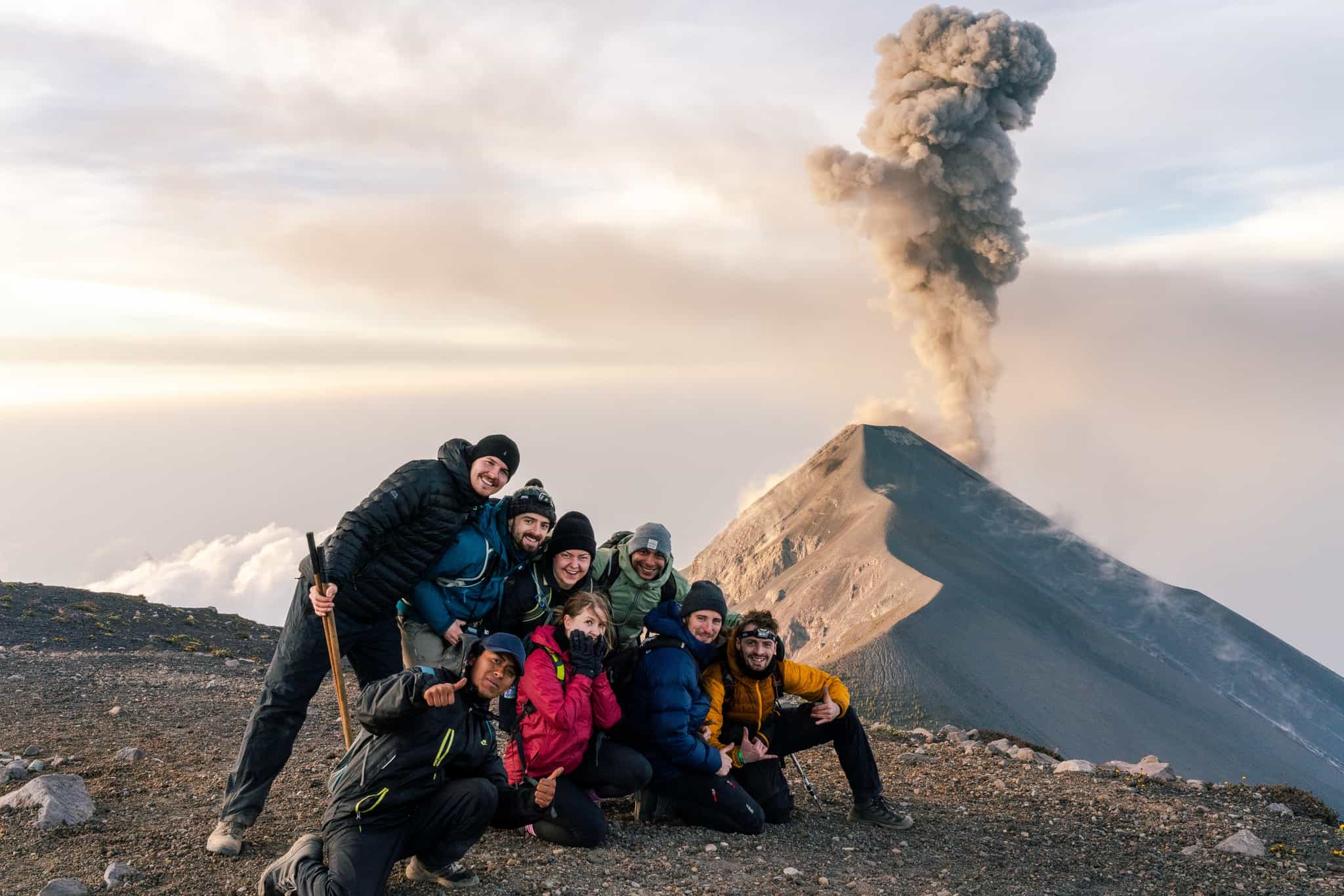 Hikers overlooking Fuego erupting from Acatenango Volcano, Guatemala