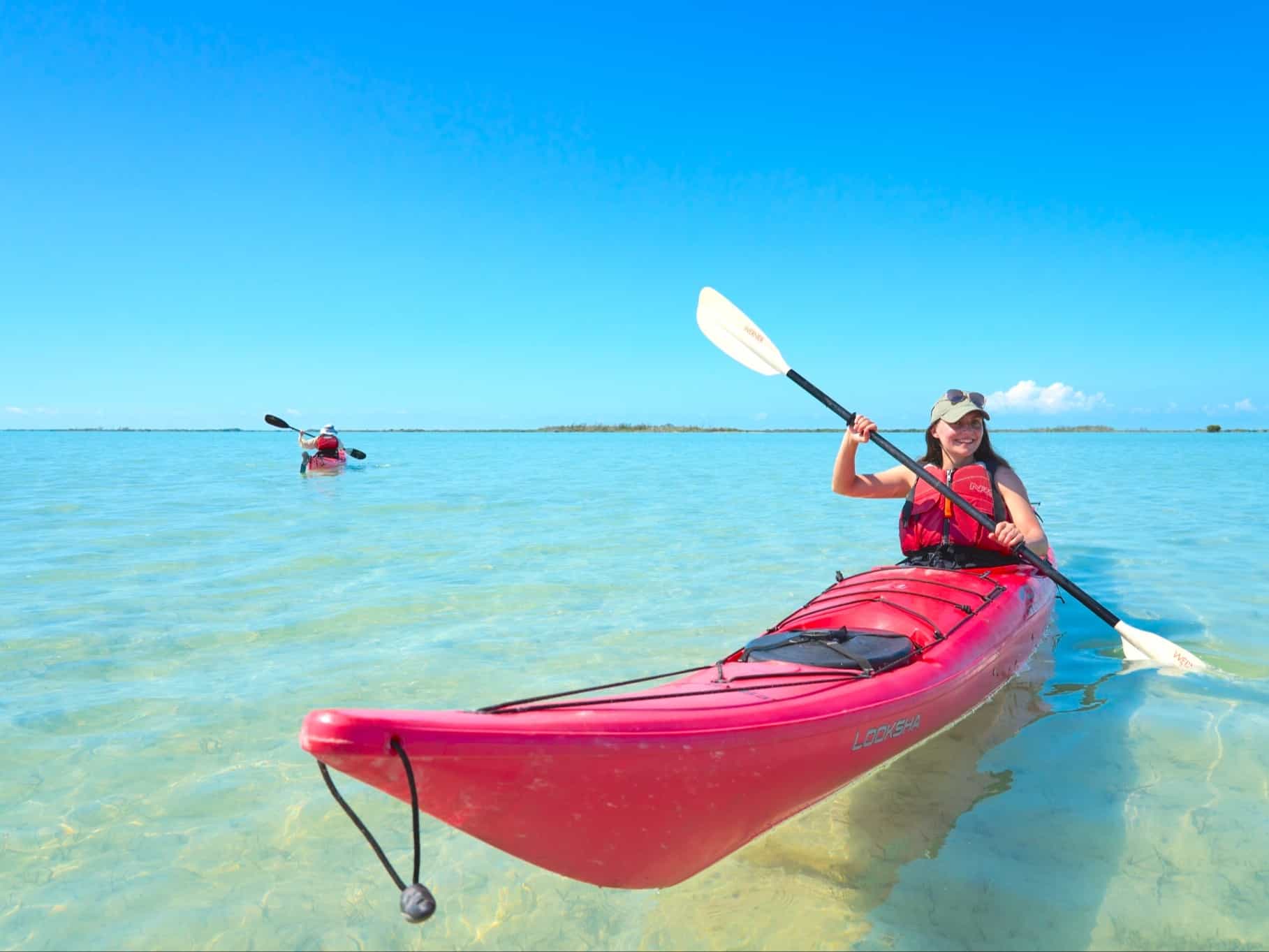 Two people kayaking on crystal clear water in Salinas de Brito, Cuba