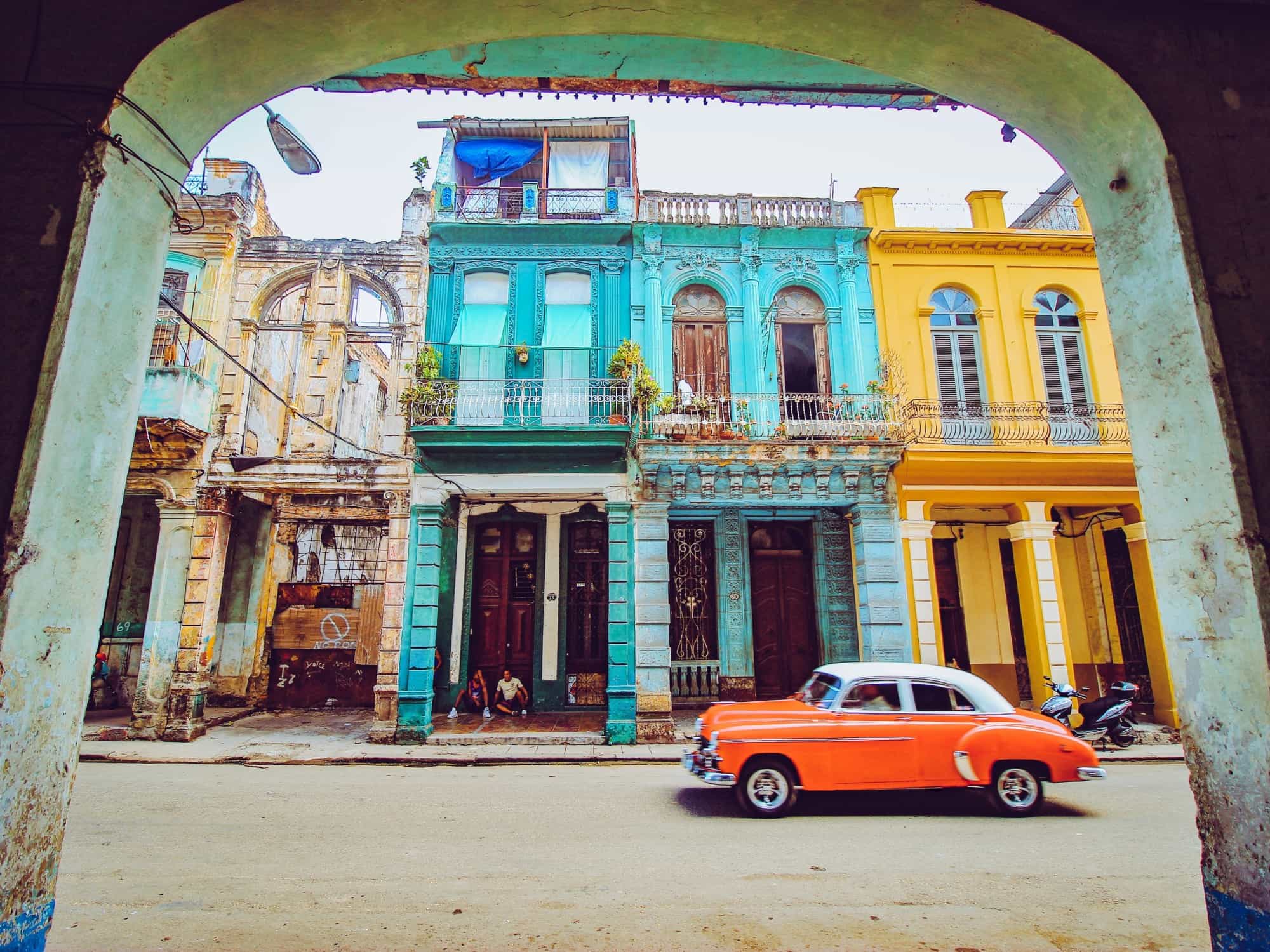 Red classic car driving through a street in Havana, Cuba