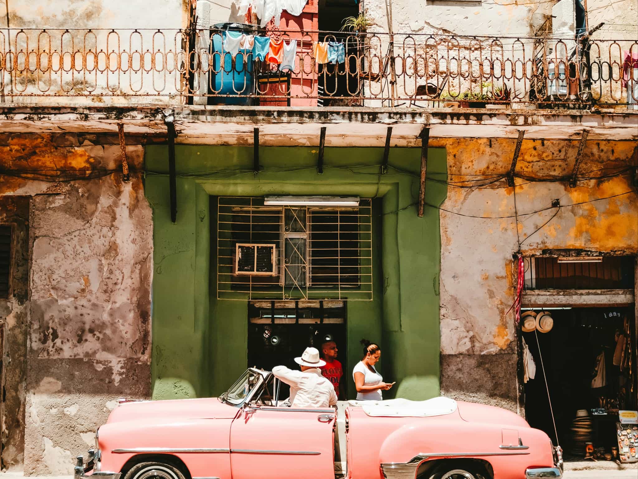 Person standing beside of pink vintage, convertible car in Cuba