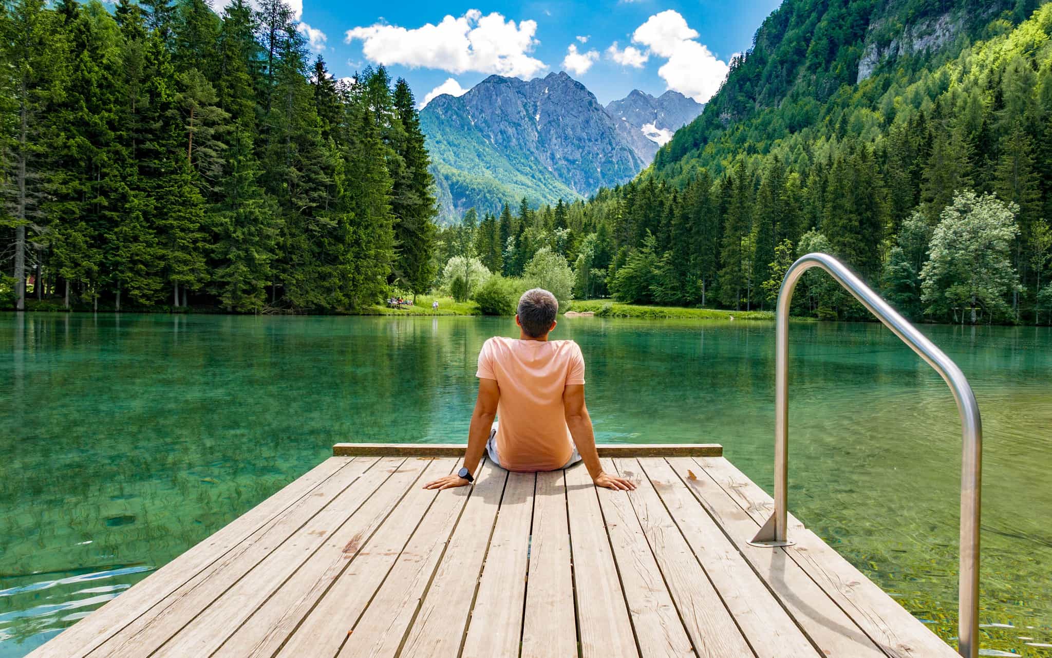 man sits by picturesque lake in slovenia