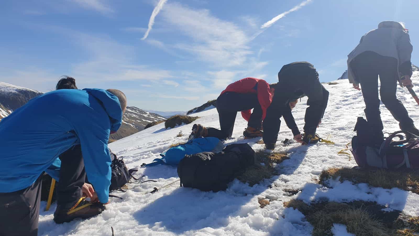 A group of people clipping on crampons on Ben Nevis, Scotland.